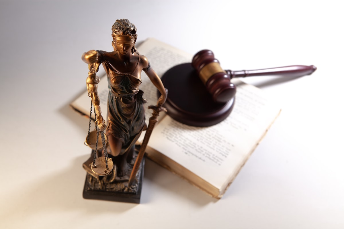 Gavel, law books and a small statue of Justice on a desk