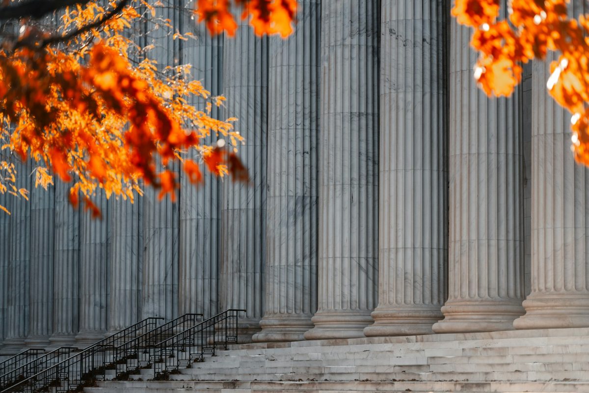 Stone columns and steps of a courthouse framed by orange autumn leaves