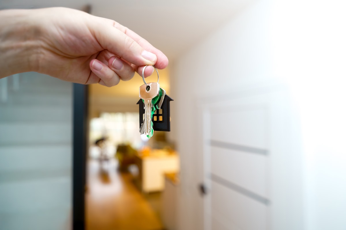A house key held in front of a front door
