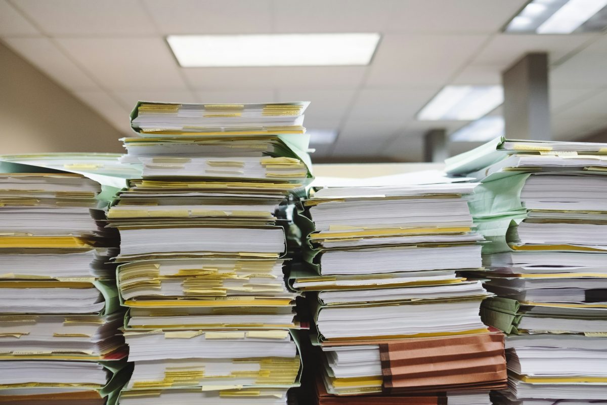Altas pilas de expedientes y carpetas de papel sobre una mesa de oficina
